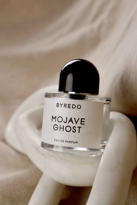 A bottle of Baccarats' "Mojave Ghost EDP for Men and Women." The cylindrical bottle with a transparent body showcases the label proudly displaying the product's name. The round black cap completes its sleek and minimalist appearance, embodying Mojave Ghost as your exotic floral signature scent.