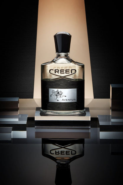 A 100ml bottle of Creed Aventus EDP by Baccarats, with its black cap and label, emphasizes the opulent ambergris notes. The label showcases an intricate design of a horse and rider, while the mostly clear bottle adorned with black accents conveys an aura of sophistication accentuated by Calabrian bergamot.