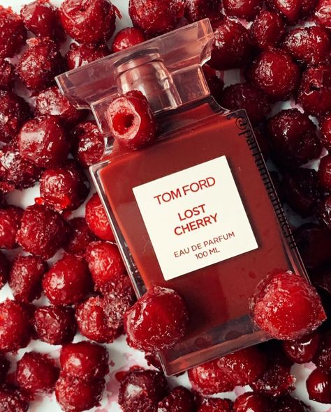 A rectangular, translucent pink bottle with a red liquid inside displays a front label that reads "TOM FORD LOST CHERRY EAU DE PARFUM 100 ML." Infused with the richness of black cherry, the bottle features a square-shaped, translucent pink cap. This unisex fragrance is offered by the brand Baccarats under the name Tom Ford Lost Cherry Eau De Parfum for Men and Women.