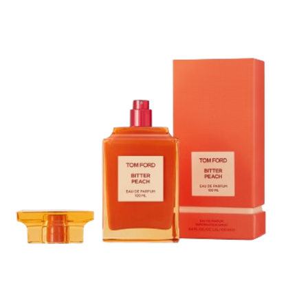 A 100 ml bottle of Baccarats Tom Ford Bitter Peach Eau De Parfum for Men and Women features a warm orange hue that reflects the luxuriant notes of Sicilian blood orange oil and sandalwood absolute, with a square label displaying both the brand and fragrance name.