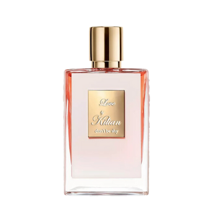 A rectangular glass bottle of By Kilian Love, Don't Be Shy perfume with a gradient pink hue, featuring a gold cap and a square gold label on the front, embossed with the text "Love by Kilian, don't be shy." Infused with delicate notes of Orange Blossom, this Baccarats fragrance captivates from the first spritz.